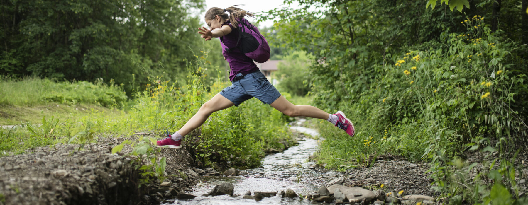 A girl jumping across a stream