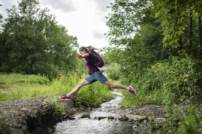 A girl jumping over a creek
