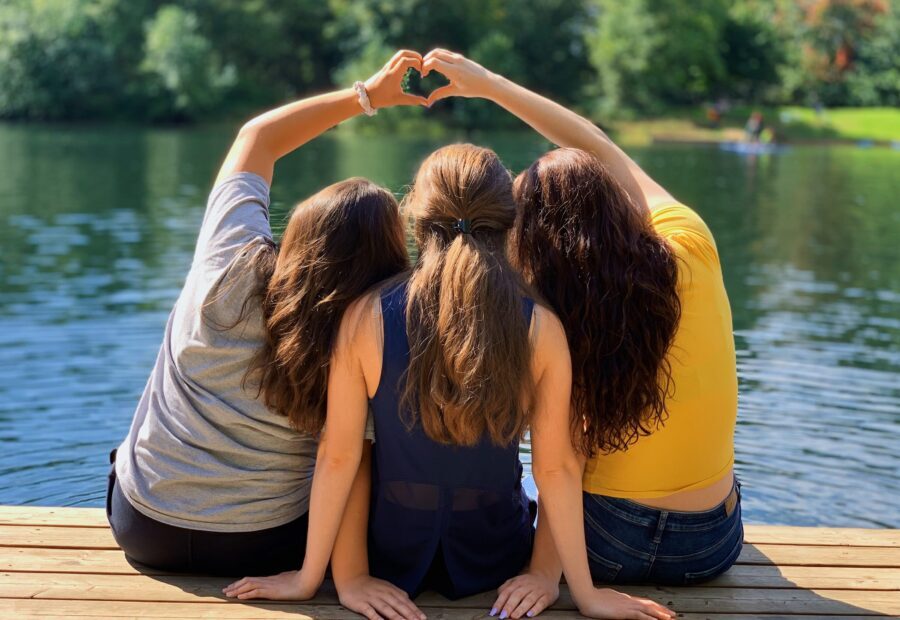 three girls on deck forming a heart with their hands