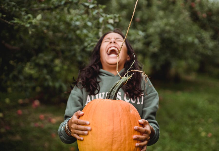 A kid laughs while holding a pumpkin